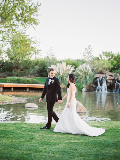 Bride and groom walking next to water
