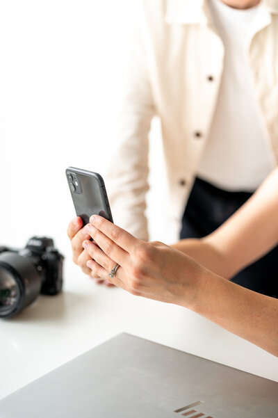 A close up shot of Kala holding her phone, showing Reg who is behind her something. You can't see either of their faces.