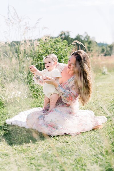 mom in beautiful floral dress with baby girl in  meadow