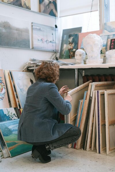 woman sorting through canvases