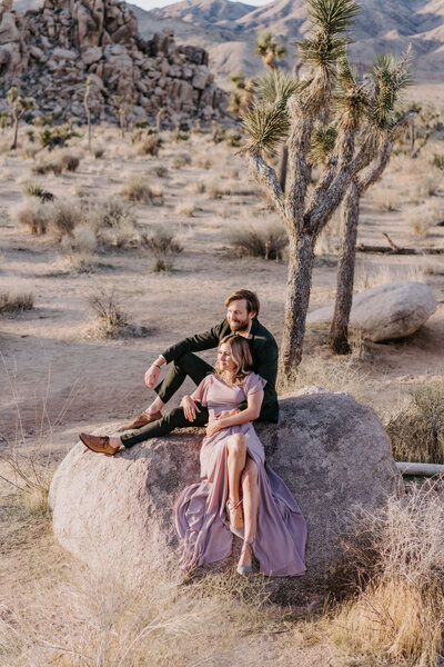 couple sitting on rock posing in Joshua Tree