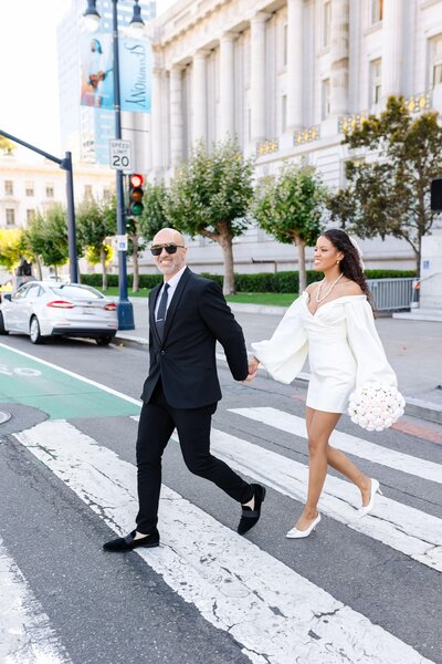 couple crossing the street in front of san francisco city hall