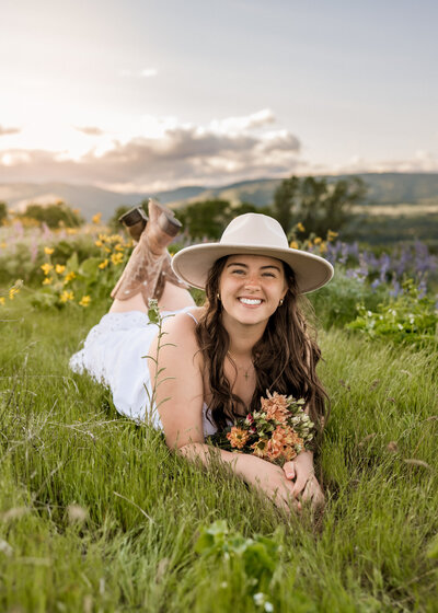 Girl laying in the grass with wildflowers around her in the Columbia River Gorge at Tom McCall Viewpoint