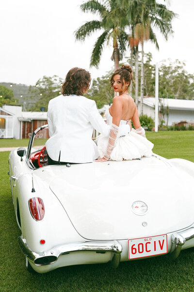 Bride and groom on back of vintage car