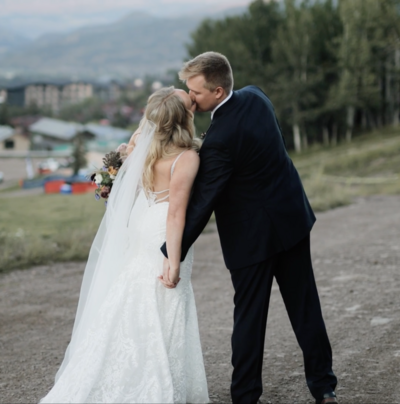 Bride and Groom at luxury wedding in Colorado hold hands and kiss