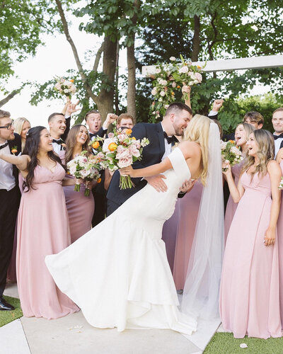 Bride and groom kissing while bridal party cheers for them