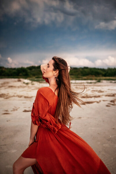 Family Photographer, Cassie Lee  wears a red dress at the beach