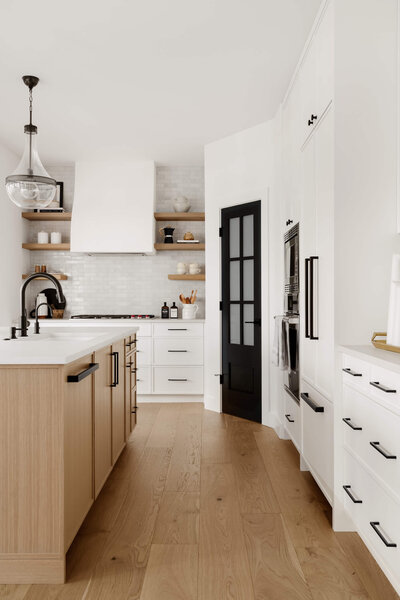 A modern farmhouse kitchen with white cabinets paired with white okay and black accents. 