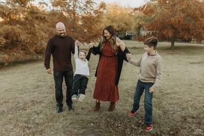 family holding hands and swinging toddler