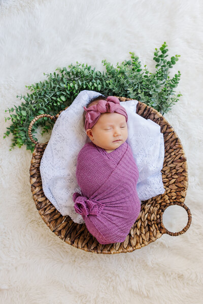 Baby girl sleeps in purple swaddle during lifestyle newborn session in Dekalb, Georgia