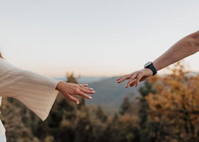 Engaged couple reaching for each other in Colorado