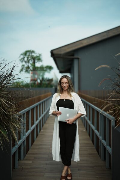 Noelle Rivet, certified hypnotherapist holding a laptop