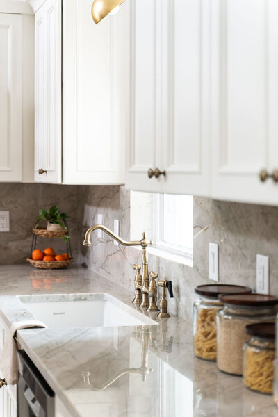 White detailed cabinetry and cristallo stone with white wainscot featured in this kitchen renovation.