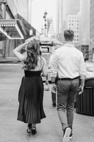 Black and white photo of engaged couple walking through the streets of New York City toward Grand Central Station during their NYC engagement session.