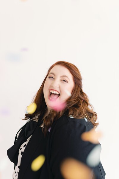 woman laughing surrounded by confetti falling