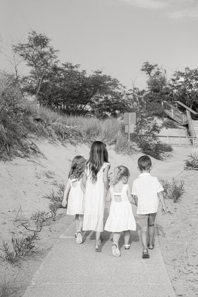 black and white portrait of a group of grandkids walking on a boardwalk during their extended family session