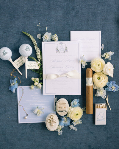 Elegant flat lay of wedding details on blue styling mat
