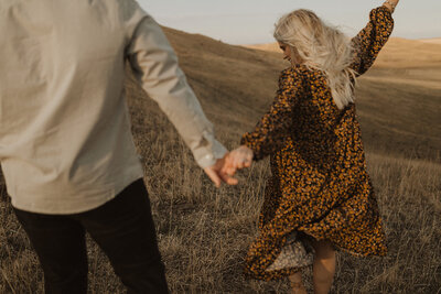 couple holds hand in field