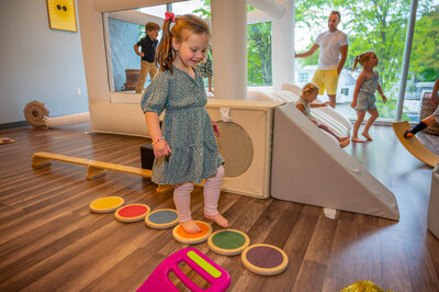 Girl smiling while walking on colorful blocks at a Hartbeeps class.