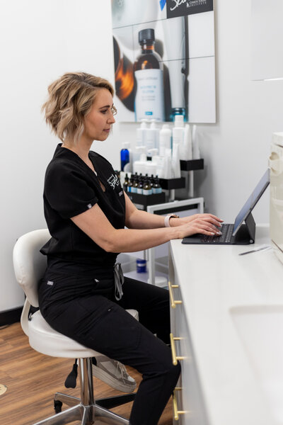 Esthetician in her salon on the computer