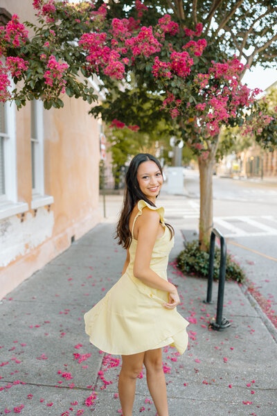 Senior portrait of a young woman standing along a Charleston sidewalk in downtown charleston.