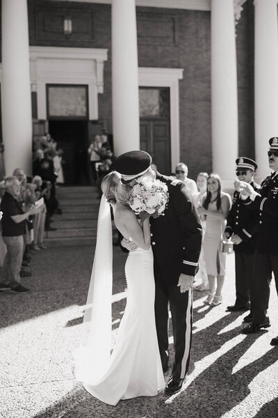 Bride and groom sharing a kiss after their military wedding ceremony, surrounded by guests, captured by a Washington wedding photographer.