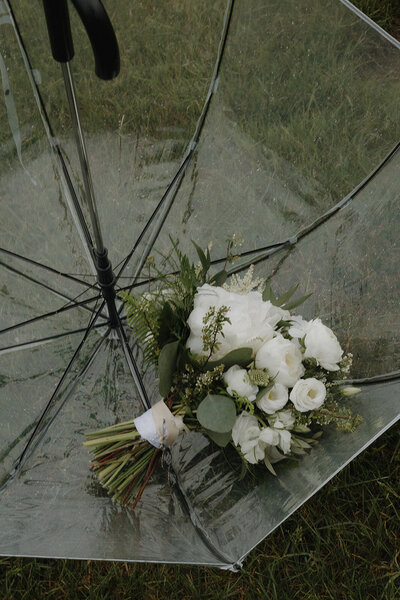 wedding bouquet sitting in a clear umbrella in grass