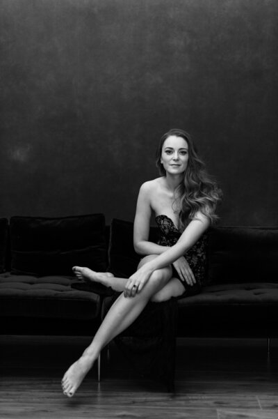 Black and white portrait of woman in a black lace dress posed sitting