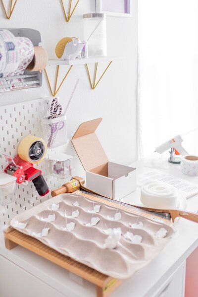 sugar flower petals sit next to shipping tape and supplies on a table