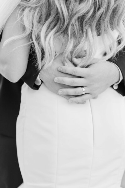 Black and white photo of groom holding bride and close up of grooms hands