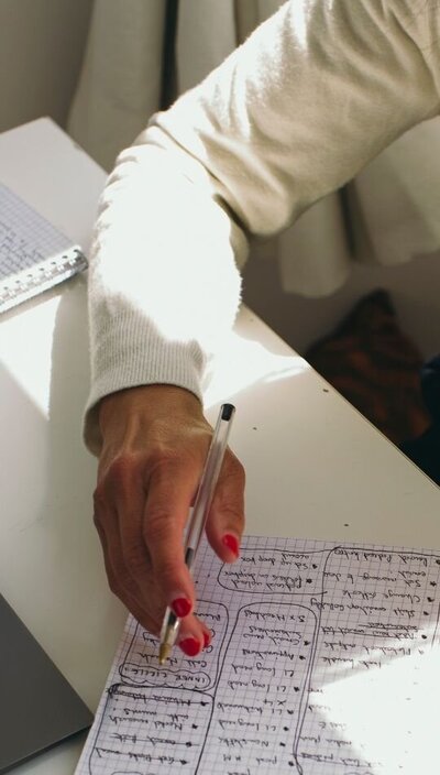 Kaya pointing at a handwritten notebook page with organized bullet points.