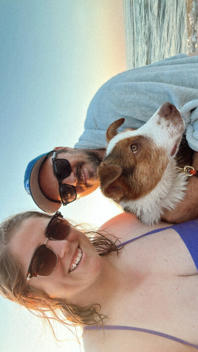 a girl, a man and a dog at the beach at sunset