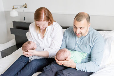 Lifestyle newborn session portrait of parents holding their twins