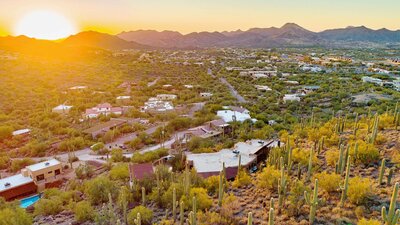Aerial view of Cave Creek, Arizona homes surrounded by desert landscape, saguaros, and mountain views at sunset.