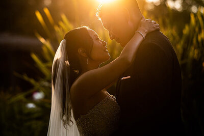 San Francisco Bay Area wedding photographer documents romantic golden hour moment as bride and groom embrace with dramatic sunset lighting at Estate Yountville