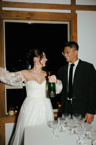 Wedding Couple popping champagne for their champagne tower with flash wedding photography