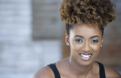 A professional headshot of a smiling woman with natural curly hair, captured by Atlanta Headshot Specialist Lynda Louis Photography