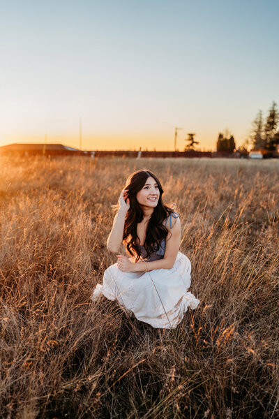 a beautiful senior girl looking directly into the camera at sunset