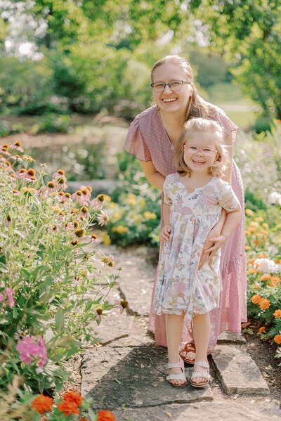 Mom in purple dress with her young daughter in a flower garden. Photos by Chicago Family Photographer Kristen Hazelton