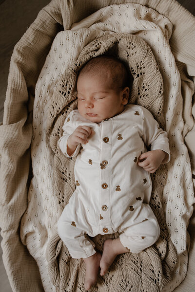 koppel geeft hun pasgeboren baby een kus op het hoofd tijfens een in-home newborn fotoshoot te Bonheiden.