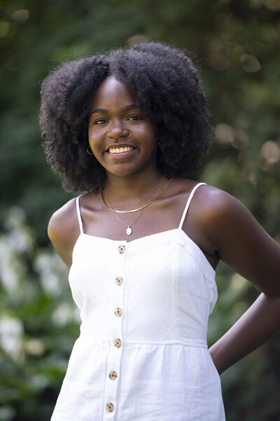 A teenager smiling with their arms behind their back 