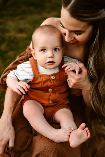 Baby in mom's lap holding her hand.
