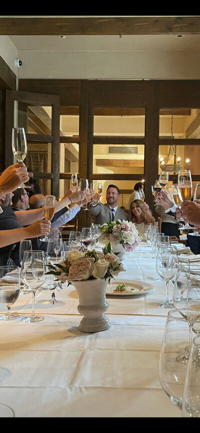 Guests raising champagne glasses in a celebratory toast at a long table