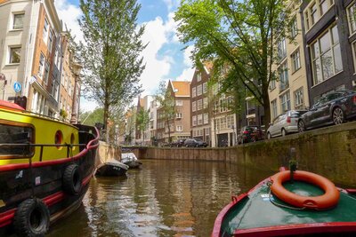 A canal boat drifting through a tree-lined waterway in Amsterdam, past gabled townhouses and brick bridges ©Stephanie Dosch | theViatrix Netherlands Private Luxury Travel