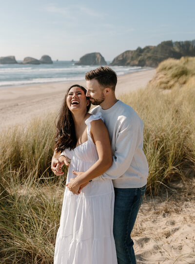 Couple laughing on Cannon Beach during their PNW engagement session.
