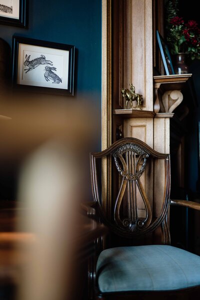 A vintage chair is photographed in the moody lounge area of Kinclune House.