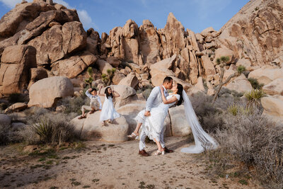Joshua Tree elopement ceremony with bride and groom exchanging vows with kids surrounded by jumbo rocks during sunset.