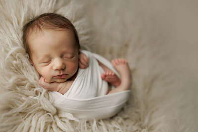 Newborn baby boy wrapped up in a cream wrap