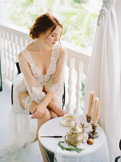 Bride in vintage inspired wedding day robe writing her vows with breakfast for a styled boudoir session from Willow and Oak