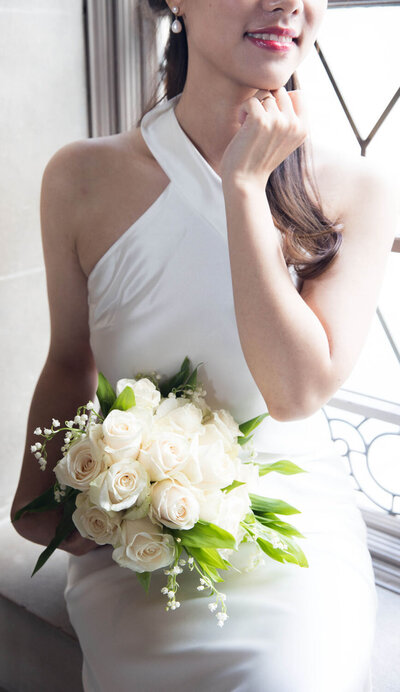 Bride in a halter gown holding a bouquet, close-up of her face and dress